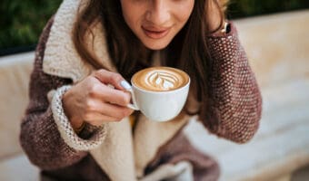 Young woman enjoying latte art coffee.